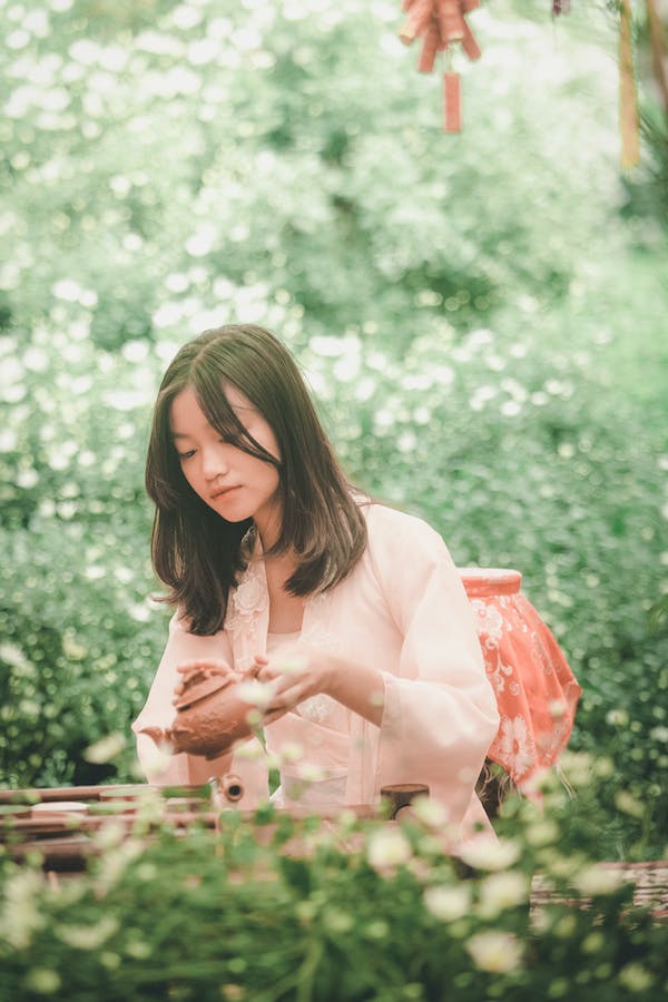 ragazza con teiera cinese in un giardino